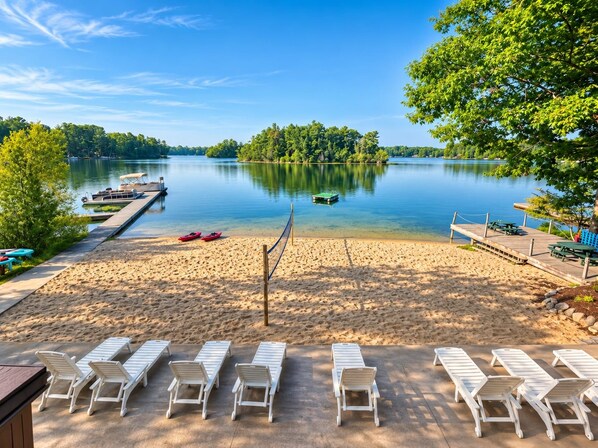 A beach with lounge chairs and a dock with boats.