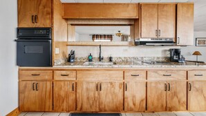 A kitchen with wooden cabinets, a black oven, a stainless steel range hood, and a granite countertop. - Fishing-Spider Lake-Sauna-Balcony-Family Friendly (Traverse City)
