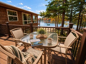 A deck with a glass table, chairs, a book, and a coffee cup.