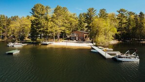 A lakeside property with a dock, a house, and boats. - Fishing-Spider Lake-Sauna-Balcony-Family Friendly (Traverse City)