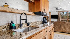 A kitchen with granite countertops, stainless steel sink, wooden cabinets, and a built-in oven. - Fishing-Spider Lake-Sauna-Balcony-Family Friendly (Traverse City)