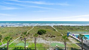 A beachfront property with a pool, a walking path, and a view of the ocean.