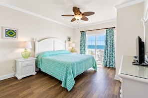 A bedroom with a bed, nightstands, a ceiling fan, a window with curtains, and a TV.