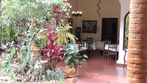 A spacious patio with potted plants, a dining area with tables and chairs, and a clock on the wall. - HOTEL REAL (Ocaña)