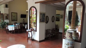 A dining area with tables and chairs, a large mirror, and a decorative vase. - HOTEL REAL (Ocaña)