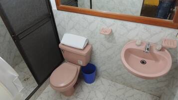 Un baño con inodoro, lavamanos y espejo.