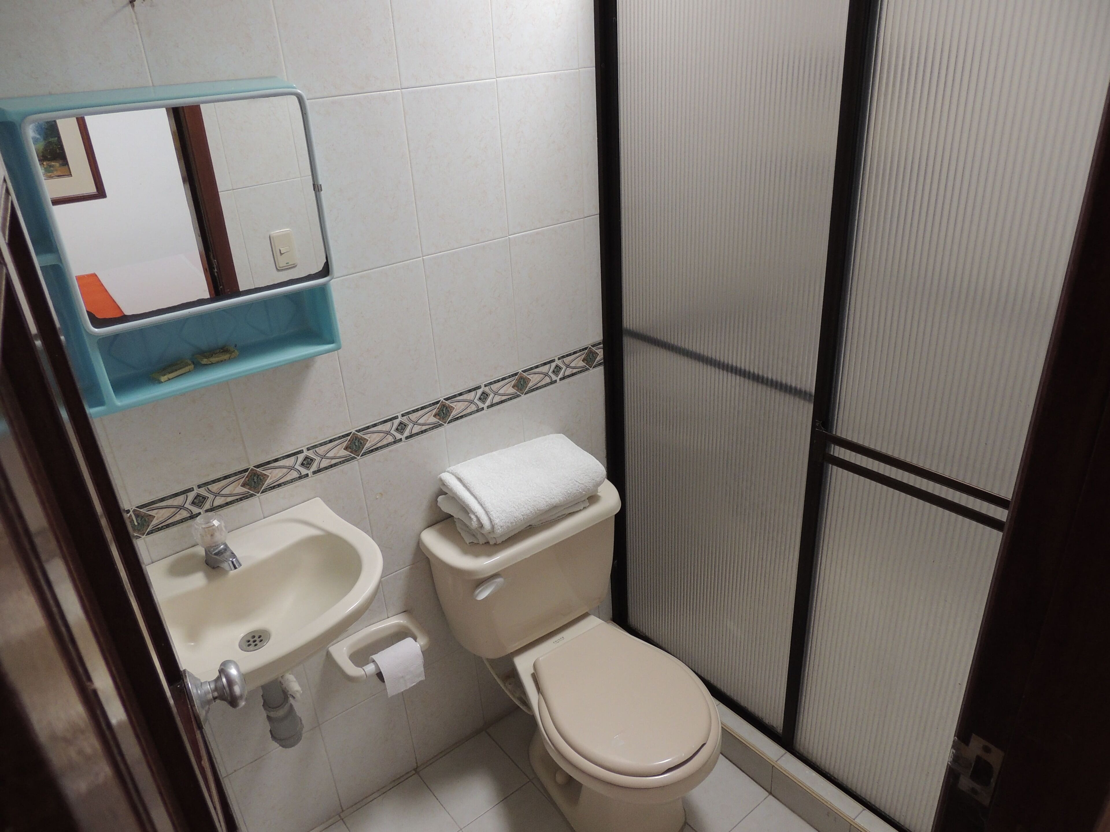 A bathroom with a toilet, sink, and a mirror above the sink.