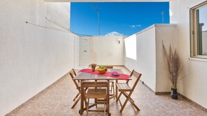 A small, enclosed patio area with a tiled floor, a wooden table with chairs, a red tablecloth, and a potted plant. - 2529 Aura Apartments - Trilo Asia PP SX by Barbarhouse (Porto Cesareo)
