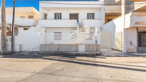 A modern two-story building with a white exterior, a gated entrance, and a staircase leading to the upper floor. - 2529 Aura Apartments - Trilo Asia PP SX by Barbarhouse (Porto Cesareo)