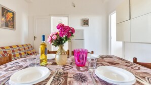 A dining table set with plates, cutlery, a vase with flowers, and a bottle. - 2529 Aura Apartments - Trilo Asia PP SX by Barbarhouse (Porto Cesareo)