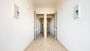 A hallway with a speckled floor, doors on both sides, and wall-mounted light switches. - 2529 Aura Apartments - Trilo Asia PP SX by Barbarhouse (Porto Cesareo)