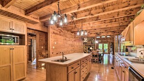 Una cocina tipo cabaña de madera con una isla central, armarios de madera e iluminación colgante.