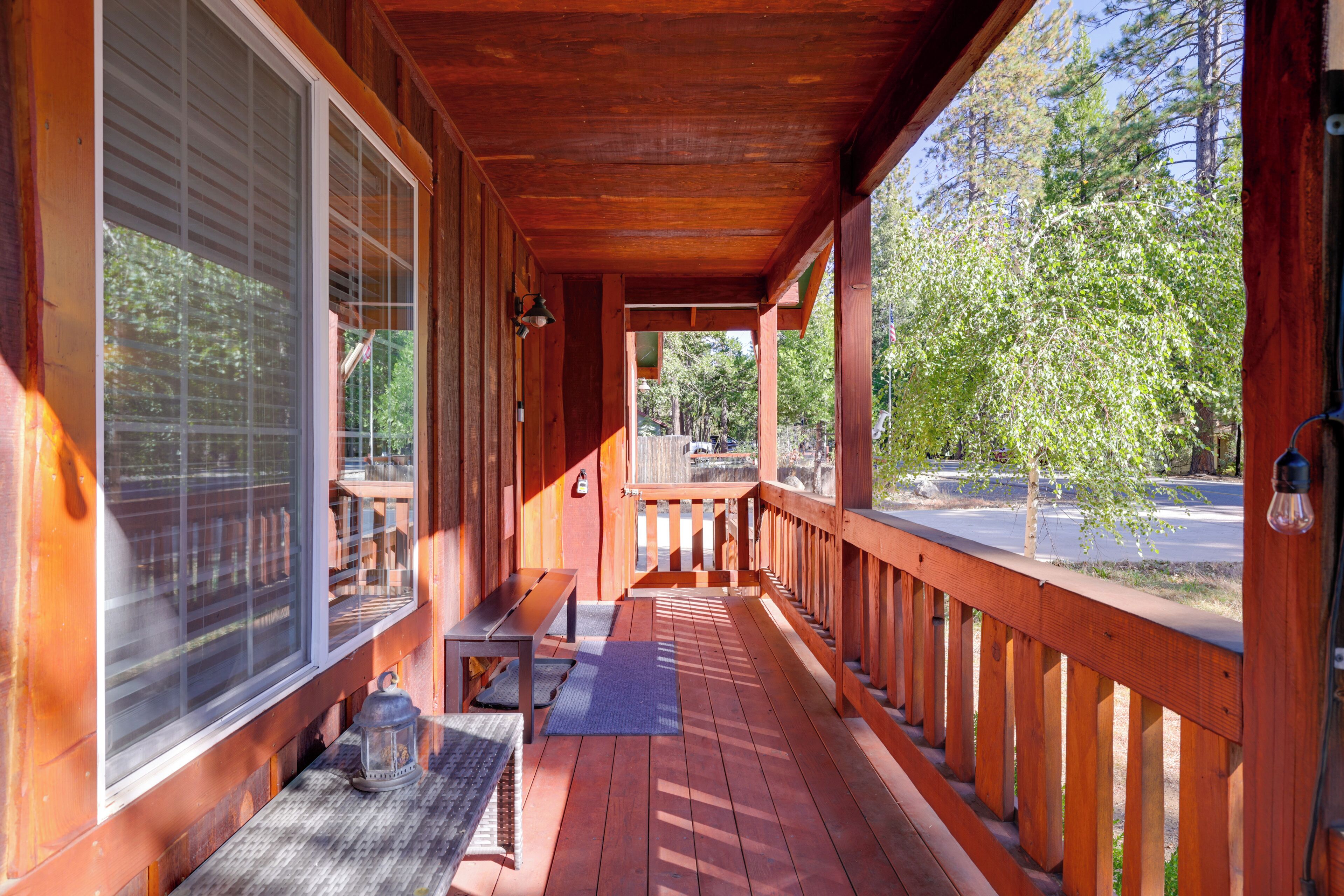 A wooden porch with a bench, a table, and a lantern.