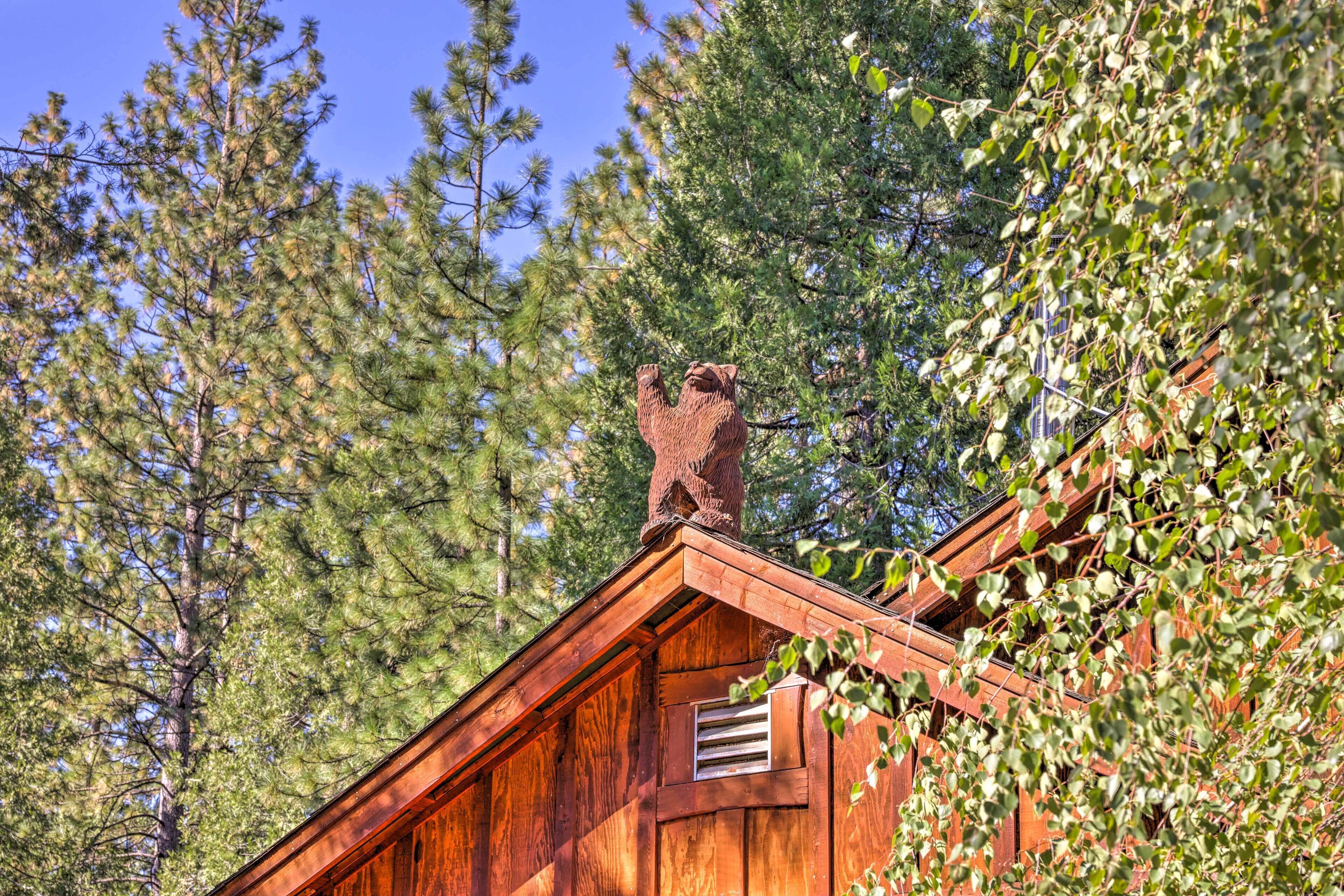A wooden cabin with a chimney, surrounded by trees.
