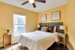 A bedroom with a bed, two bedside tables, a ceiling fan, a window, and a small cabinet. - Chic Indianapolis Home w/ Yard Near Downtown! (Indianapolis)
