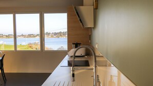 A modern kitchen with a large window, a sink, and a coffee maker. - Villa Avec vue Mer, Piscine Chauffée (Landéda)