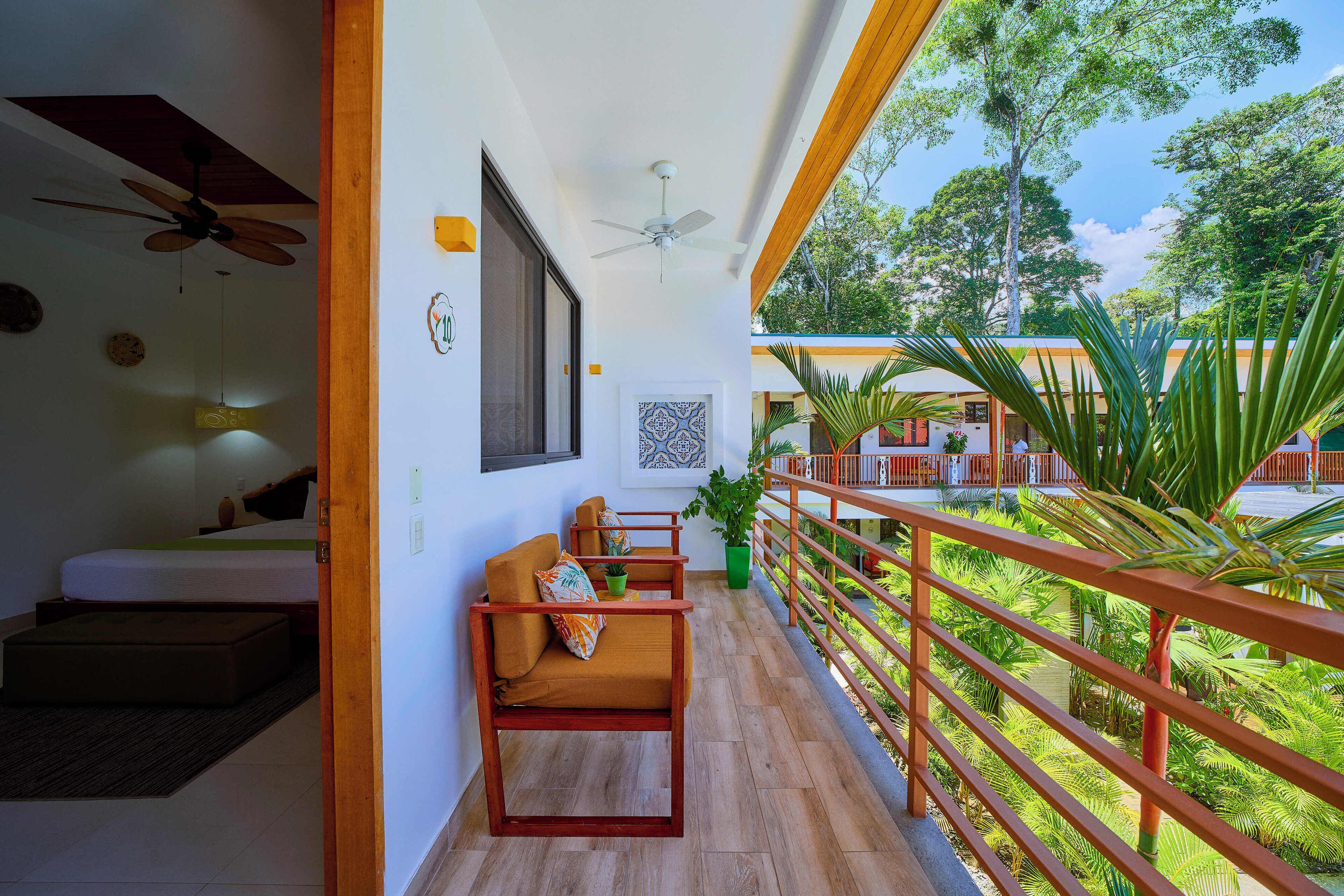 A balcony with wooden railings, a ceiling fan, and a view of lush greenery.