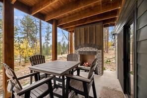 An outdoor patio with a brick fireplace, wooden table, and chairs. - Make Time Lodge- Clubhouse Access, Outdoor fireplace/Seating, Hot Tub, & Garage  (Lead)