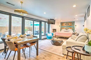 A modern living room with a dining area, large windows, a flat-screen TV, and a cozy sofa. - Luxury Spa Retreat: Private Courtyard & More! (Hastings)