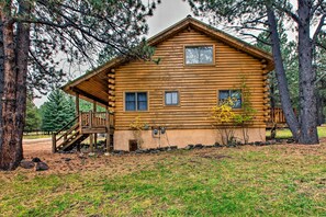 Situated in a secluded wooded area, this cabin features a charming front porch with a staircase.