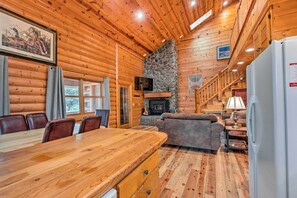 Cozy cabin interior with a dining table, fireplace, and comfortable sofa, perfect for relaxation and dining.