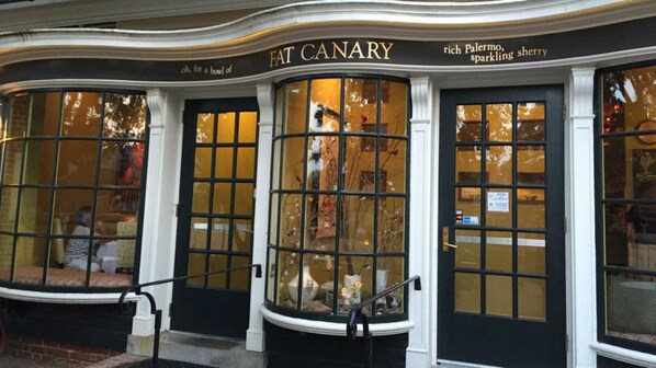 Welcome to Fat Canary, where a charming entrance beckons with a vibrant display of fresh produce and a hint of fine spirits.