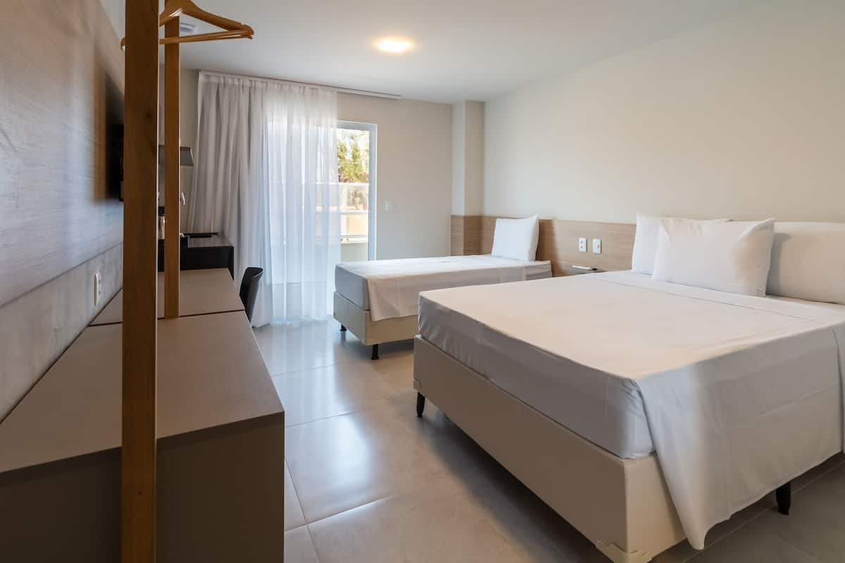 A hotel room with two beds, a desk, and a chair.