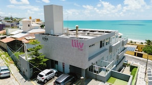 A modern building with a rooftop, adjacent to a body of water, featuring a sign with 'ATMA ROOFTOP' and 'liiv mar' branding. - Liiv Mar - Natal Ponta Negra (Natal)