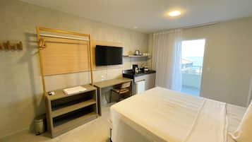 A hotel room with a bed, a desk, a chair, a TV, and a balcony with a view.