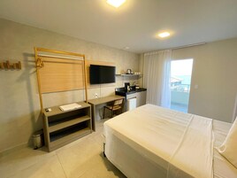 A hotel room with a bed, a desk, a chair, a TV, and a balcony with a view.