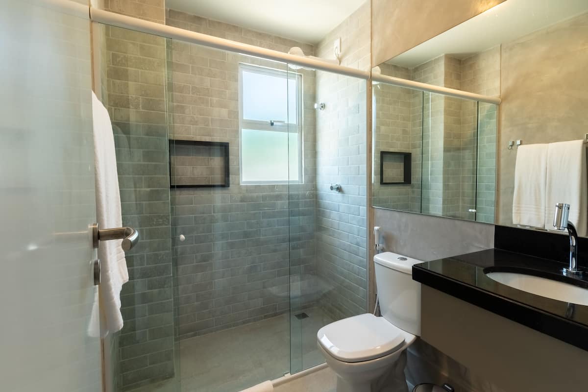 A modern bathroom with a glass-enclosed shower, a toilet, and a sink with a black countertop.