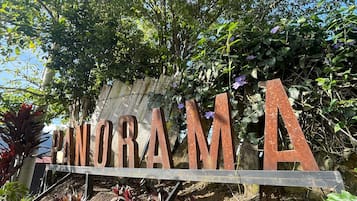 Un letrero con la palabra 'PONORAMA' en letras grandes, rodeado de follaje y plantas.