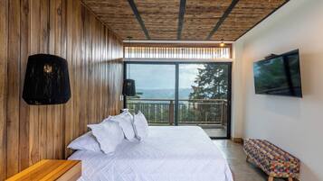 Une chambre moderne avec un plafond en bois, un grand lit avec une literie blanche, un banc et un téléviseur fixé au mur.