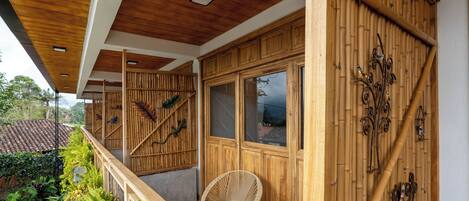 A wooden balcony with a woven chair and a wooden table.