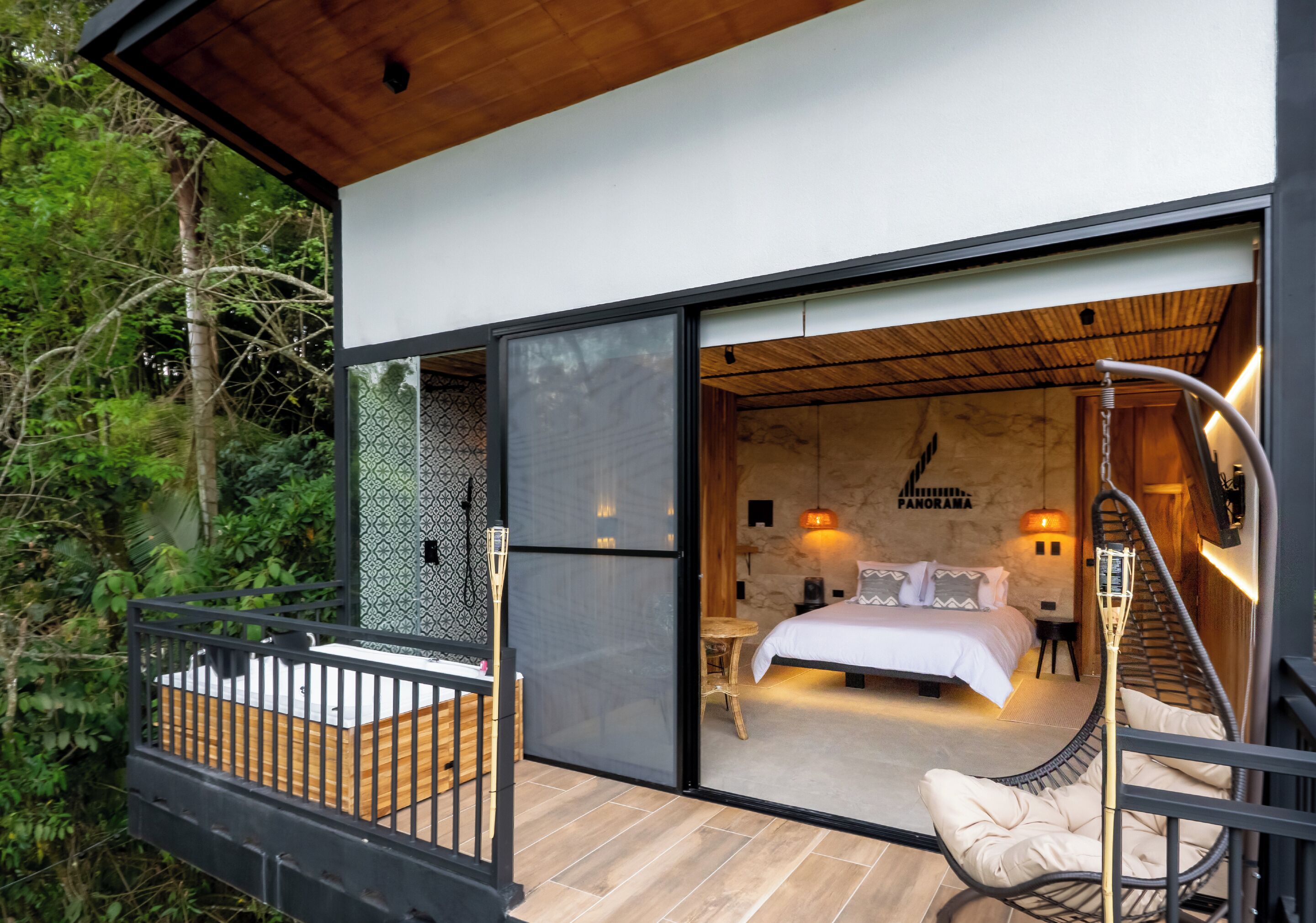 A modern bedroom with a bed, bedside table, and a hanging chair.