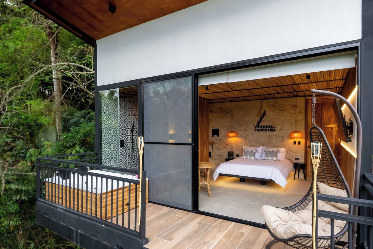 A modern bedroom with a bed, bedside table, and a hanging chair.