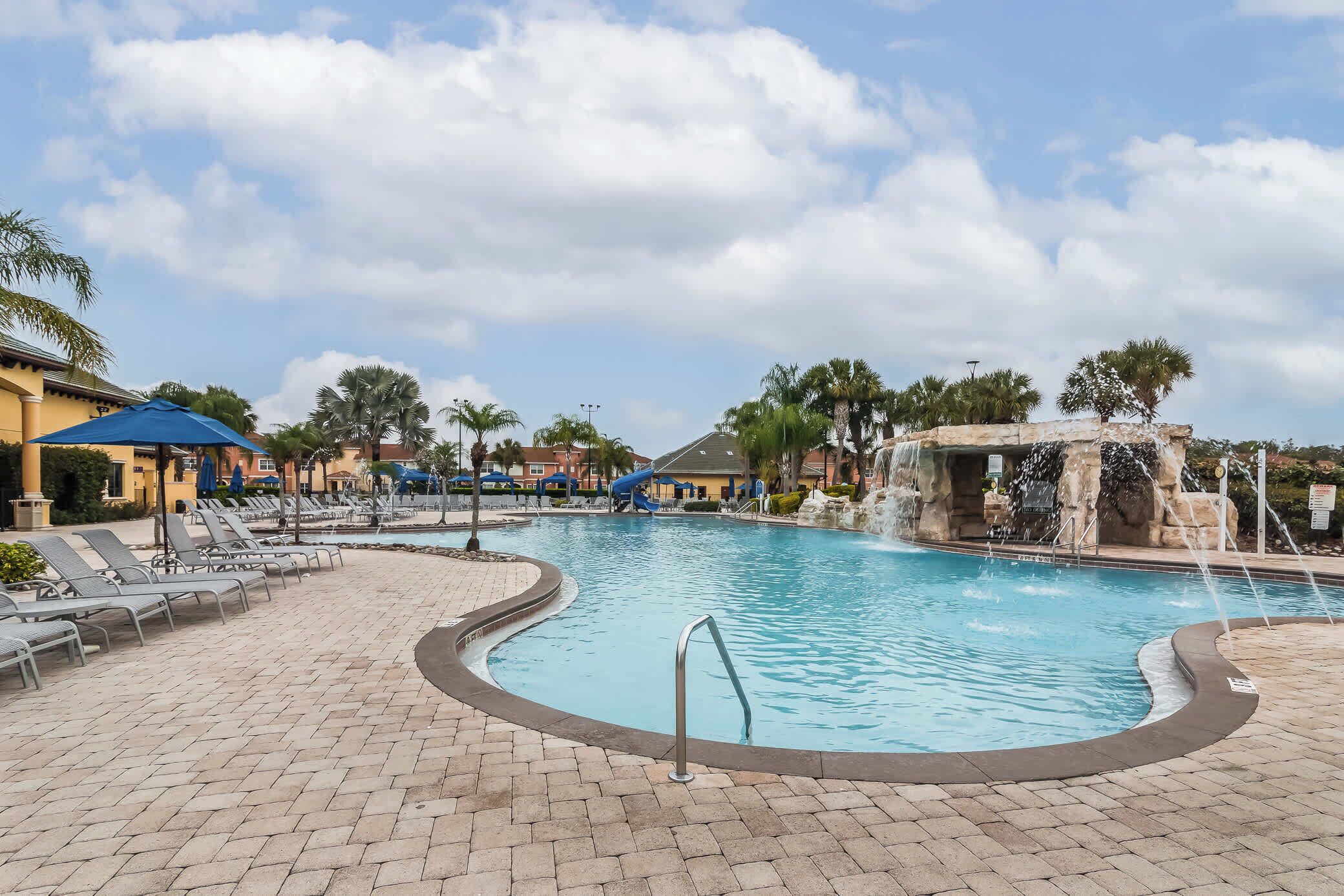 A swimming pool with lounge chairs and a waterfall feature.
