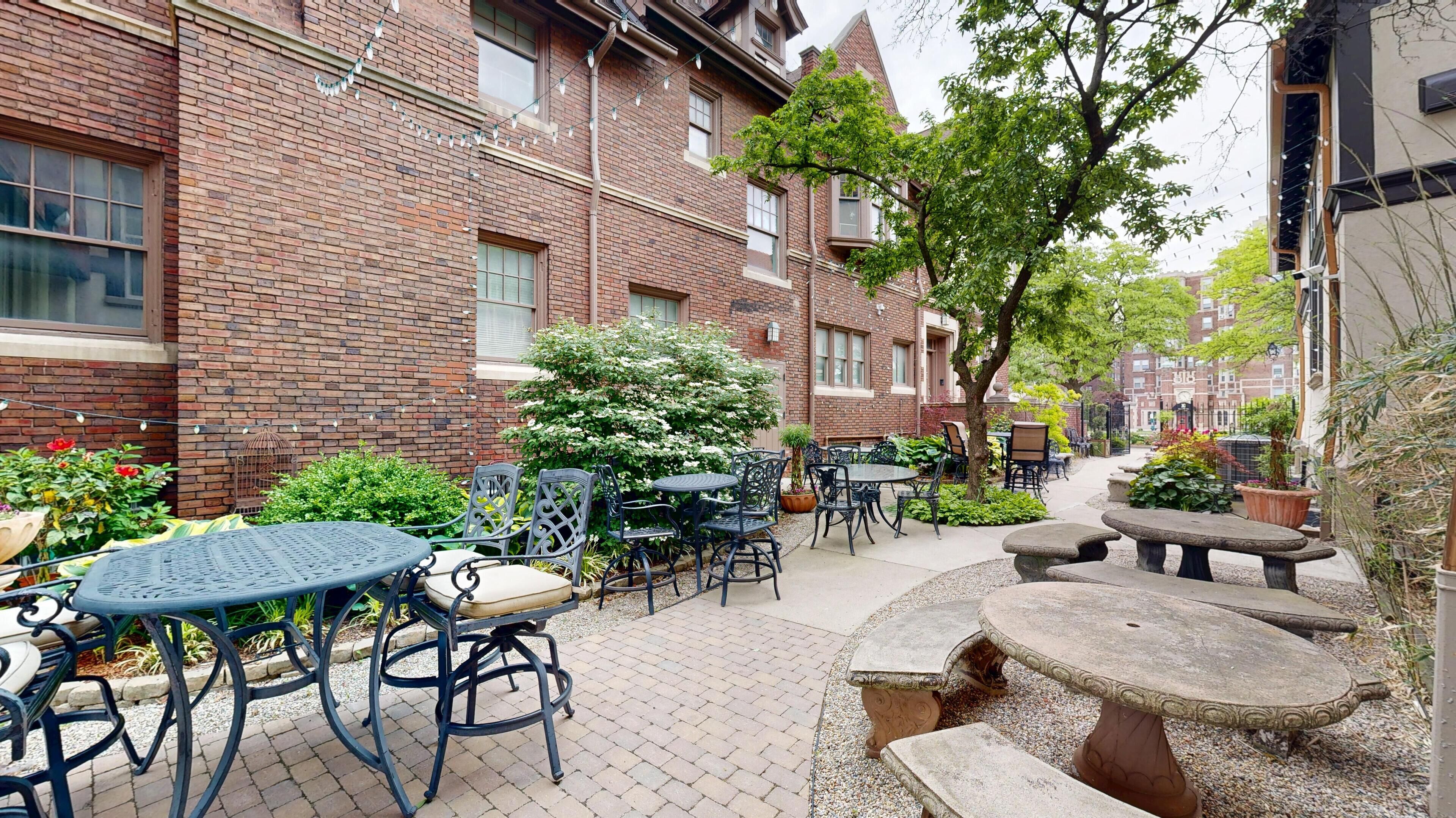 A courtyard with outdoor seating, brick buildings, and greenery.