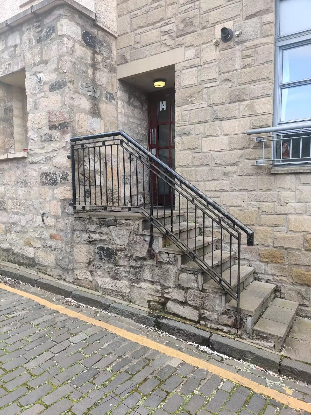 A stone building with a metal staircase leading to a door marked with the number 14.