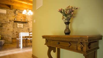 Una mesa de madera con un jarrón de flores secas, una pared de piedra y un techo de madera en una habitación.