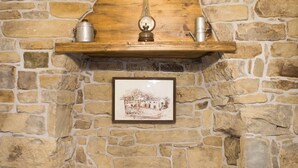 A stone wall with a wooden shelf holding a metal pot, a framed picture, and a small wooden chest. - Apartment Baladur (Koper)