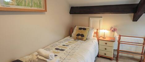 Une chambre à coucher avec un lit, une table de chevet, une lampe, un radiateur et une carte accrochée au mur.
