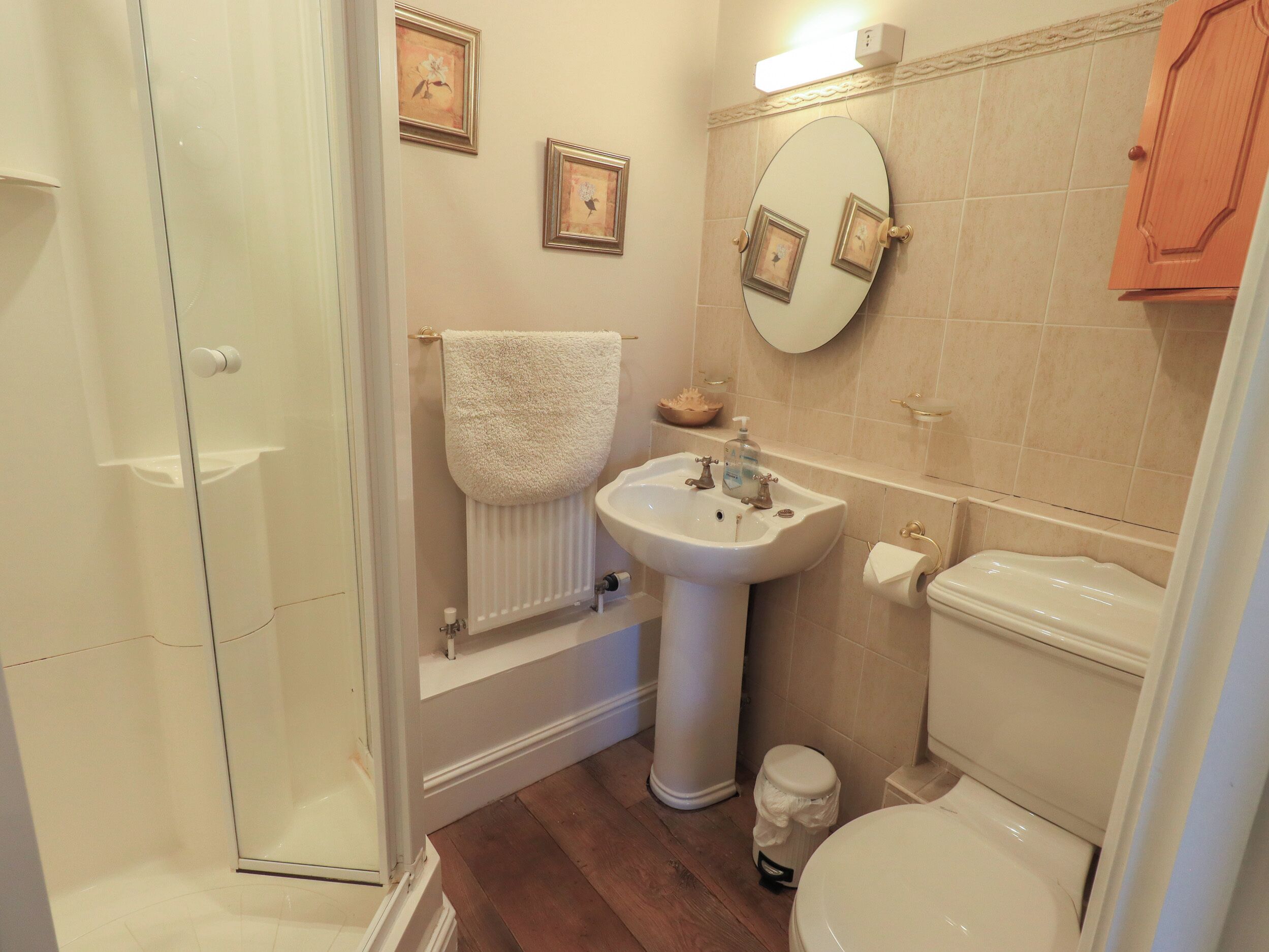 Une salle de bain équipée d’une douche, d’un lavabo, de toilettes et d’un miroir orné de cadres avec des photos.