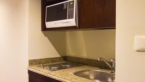 A kitchen with a microwave, granite countertop, stainless steel sink, and wooden cabinets. - Porto Sharm Hotel Apartments (Sharm El Sheikh)