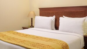 A hotel room with a large bed, a wooden headboard, a bedside table with a lamp, and a framed artwork on the wall. - Porto Sharm Hotel Apartments (Sharm El Sheikh)