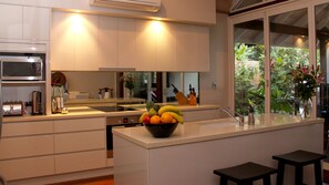 Una cocina moderna con una isla central, microondas y un ventanal con vistas al paisaje verde.