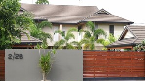 Una casa de dos pisos con fachada gris, cerca de madera y un letrero que indica '2/2B'.