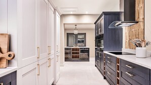 Une cuisine moderne avec des meubles blancs, des éléments décoratifs en bois foncé et des appareils électroménagers en acier inoxydable.