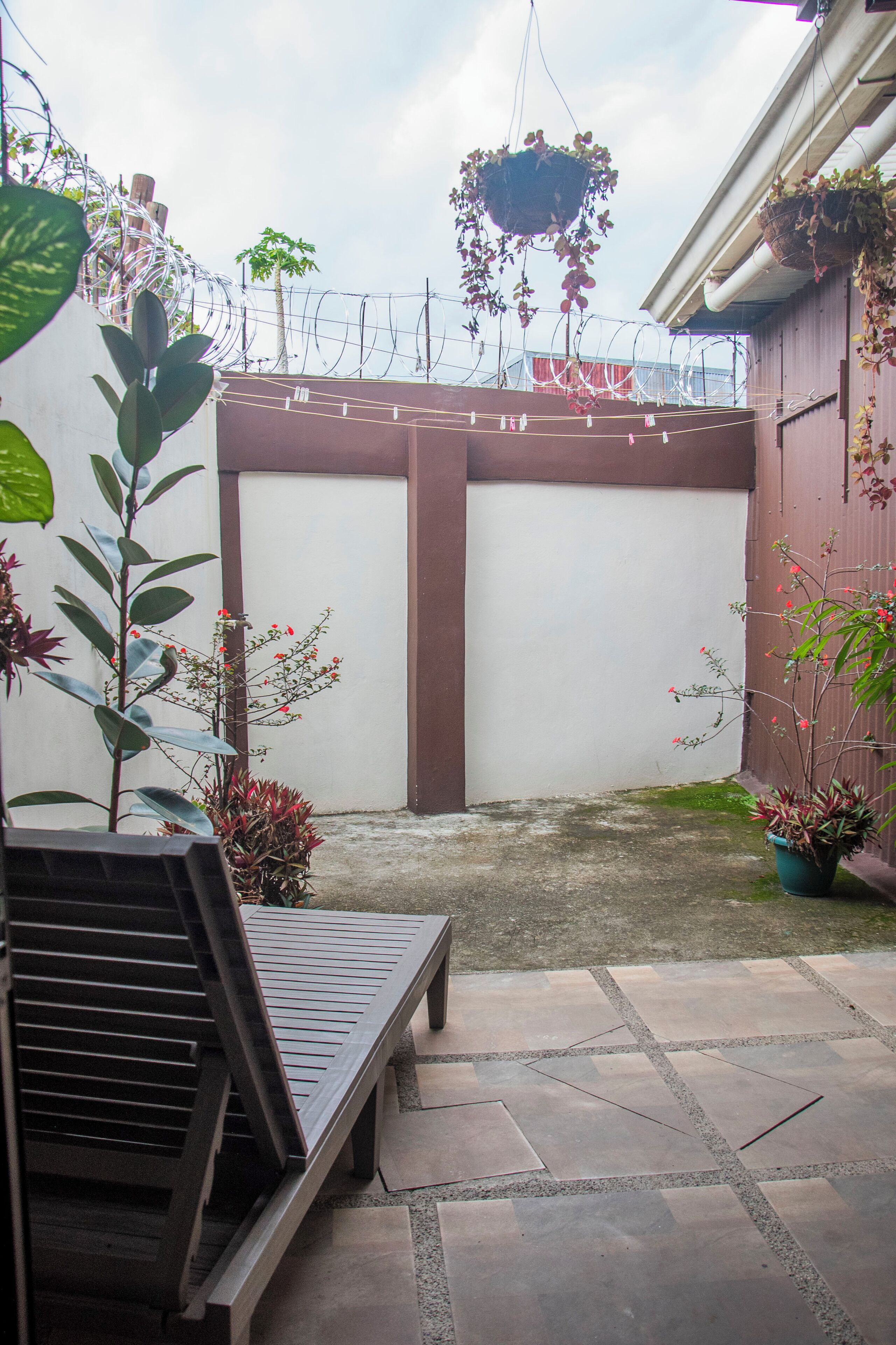 A patio area with a wooden bench, potted plants, and hanging planters.
