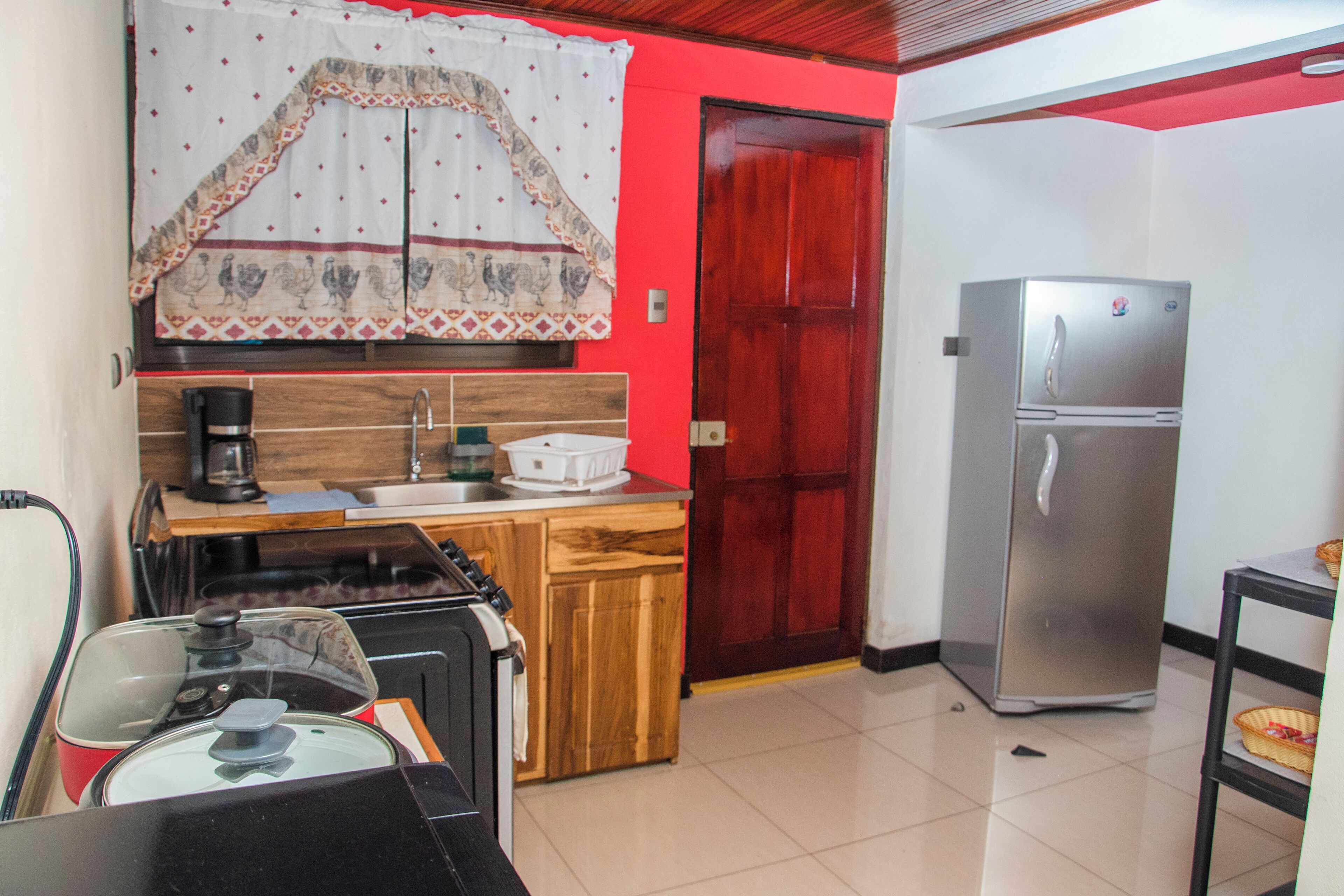 Uma cozinha compacta com cafeteira, pia, geladeira e bancada de madeira.
